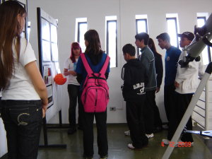 Imagem da Exposio sobre Astronomia com alunos atentos s explicaes das alunas responsveis